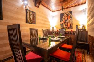 a dining room with a wooden table and chairs at Dar Alhambra Riad Medina in Marrakech