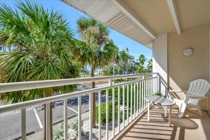 a balcony with two chairs and palm trees at Palm Terrace Waterfront Htd Pool Hot Tub Tennis in Gulf City