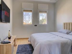 a bedroom with a bed and a desk and two windows at jaws wave agadir 2 in Agadir