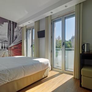 una camera con un grande letto e porte scorrevoli in vetro di Lisbon City Apartments & Suites by City Hotels a Lisbona