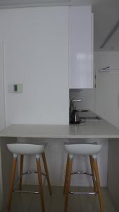 a kitchen with two white bar stools at a counter at ITowers Luxury Apartment 2 in Gaborone