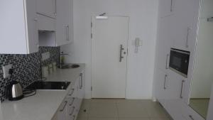 a white kitchen with white cabinets and a tv at ITowers Luxury Apartment 2 in Gaborone
