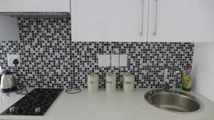 a kitchen with a sink and a black and white tile wall at ITowers Luxury Apartment 2 in Gaborone