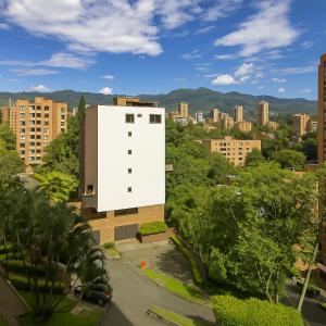 a white building with a city in the background at Edificio La Frontera - Vista El Poblado Free Parking & Wifi Recep 24 h in Medellín