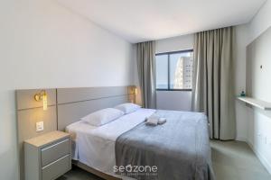 ein Schlafzimmer mit einem Bett mit weißen Laken und einem Fenster in der Unterkunft Apto Novo a 150m da Praia de Pereque CLE1202 in Perequê