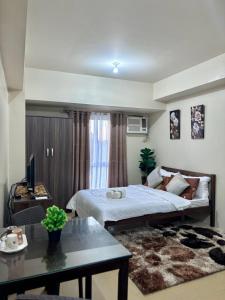een slaapkamer met een bed, een tafel en een televisie bij New Lovely Studio adj Ayala CDO in Cagayan de Oro