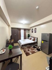 een slaapkamer met een bed en een tafel en een koelkast bij New Lovely Studio adj Ayala CDO in Cagayan de Oro