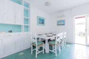 a white kitchen with a white table and chairs at VILLA LILLA Beachfront - Sea View with Parking and Private Garden in Anzio +18 photos