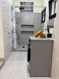 a white bathroom with a shower and a sink at Golden Sunset - Appart'Hôtel in Antananarivo