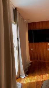 ein Wohnzimmer mit weißen Vorhängen und einem TV in der Unterkunft Apartamento novo in Itaquatiara