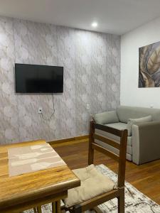 ein Wohnzimmer mit einem Sofa und einem Fernseher an der Wand in der Unterkunft Apartamento novo in Itaquatiara