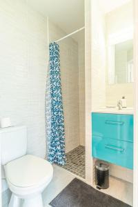 a bathroom with a toilet and a blue shower curtain at Le Refuge marin Douce escapade à 100m de la mer in Luc-sur-Mer +6 photos