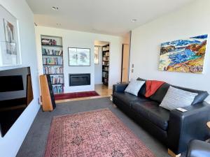 een woonkamer met een zwarte bank en een open haard bij Executive Home with Stunning Harbour views in Diamond Harbour