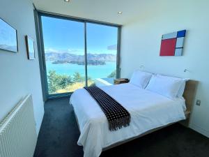 een slaapkamer met een bed en een groot raam bij Executive Home with Stunning Harbour views in Diamond Harbour +17 foto's