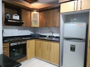 a kitchen with a white refrigerator and wooden cabinets at Casa Belmonte Pereira, Amplia, con Garaje y cerca a ExpoFuturo in Estación El Salto