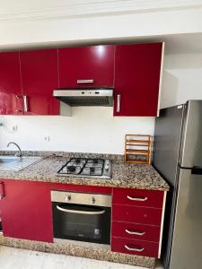 - une cuisine avec des placards rouges et une cuisinière dans l'établissement Maison Vacances, à Casablanca