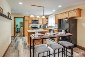 a kitchen with wooden cabinets and a island with bar stools at 1 Mi to Main St! Family Farmhouse in West Unity in Holiday City