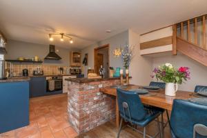 a kitchen with a wooden table and blue chairs at Cefn-Isaf in Llanbedr +20 photos