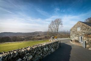 a stone house with a stone wall next to a field at Cefn-Isaf in Llanbedr