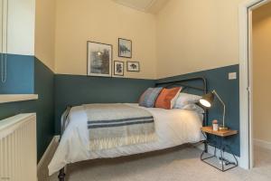 a bedroom with a bed with a blue accent wall at Pwerdy in Betws-y-coed