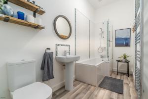 a white bathroom with a sink and a mirror at Pwerdy in Betws-y-coed +25 photos