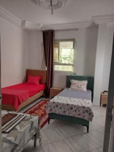 a bedroom with two beds and a window at Location saisonnière un salon et deux chambres in Raʼs al Jabal