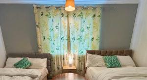 ein Schlafzimmer mit zwei Betten und einem Fenster mit Vorhängen in der Unterkunft 2 Bed House-Sleeps 4-Free Parking in Coseley