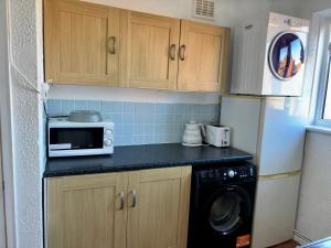 eine kleine Küche mit Mikrowelle und Geschirrspüler in der Unterkunft 2 Bed House-Sleeps 4-Free Parking in Coseley