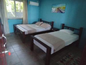 Dos camas en una habitación con paredes azules y una ventana. en Buccaneer Resort, en Bocas Town