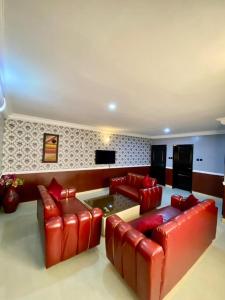- un salon avec des canapés en cuir rouge et une télévision dans l'établissement Just Ask Hotel & Suites, à Lekki
