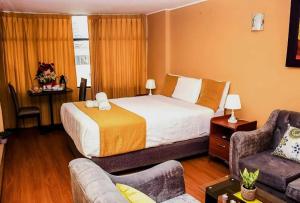 アレキパにあるHotel San Lazaro con Cocheraのベッドとソファのあるホテルの部屋