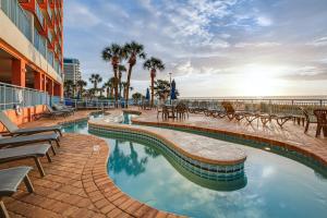 a swimming pool next to a building and the ocean at Steps to Boardwalk Condo with Pool in Myrtle Beach in Myrtle Beach
