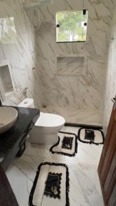 a white bathroom with a toilet and a sink at Casa Vale dos Peões Lumiar 3 in Nova Friburgo +1 photo
