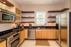 a kitchen with wooden cabinets and a stainless steel refrigerator at Pomegranate Cottage in West Bay