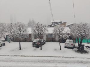 two cars parked in a parking lot in the snow at Los Lúpulos Departamentos Privados in El Bolsón