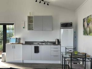 a kitchen with white cabinets and a table and a refrigerator at Whangaroa Casa Roca Studio in Whangaroa