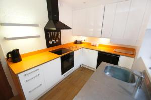 una cucina con armadi bianchi e piano di lavoro giallo di The Edge - Parking - by Brighton Holiday Lets a Brighton & Hove