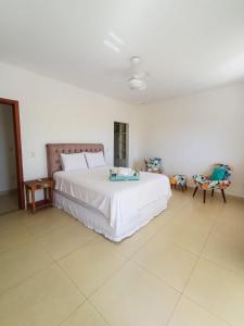 1 Schlafzimmer mit einem großen weißen Bett und 2 Stühlen in der Unterkunft Buzios casa porto da barra in Búzios
