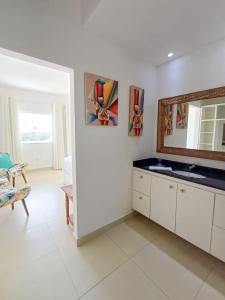 ein weißes Badezimmer mit einem Spiegel und einem Waschbecken in der Unterkunft Buzios casa porto da barra in Búzios