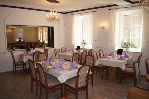 Hotel Draschwitz في Draschwitz: غرفة طعام مع طاولات وكراسي مع مناديل أرجوانية