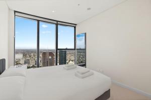 1 dormitorio con cama blanca y ventanas grandes en Panoramic Views Apartment & High-Rise Pool and Gym, en Brisbane