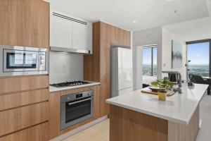 cocina con armarios de madera y encimera blanca en Panoramic Views Apartment & High-Rise Pool and Gym, en Brisbane