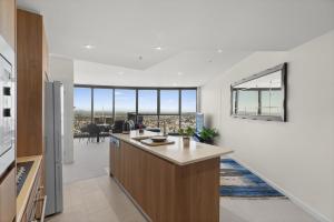 Una cocina abierta con paredes blancas y grandes ventanales. en Panoramic Views Apartment & High-Rise Pool and Gym, en Brisbane