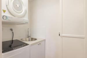 a small white kitchen with a sink and a window at Sunset Towers 11, 25 Donald St - stunning water views, air con, Wi-Fi and Linen provided in Nelson Bay