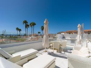 a patio with white chairs and umbrellas at FaroQuilla Suites Pasito Blanco in Pasito Blanco