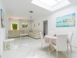 a white living room with a table and chairs at FaroQuilla Suites Pasito Blanco in Pasito Blanco