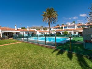 a villa with a swimming pool and a palm tree at FaroQuilla Suites Pasito Blanco in Pasito Blanco