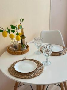 a white table with two plates and glasses on it at Cozy studio with a balcony and sea view in Batumi