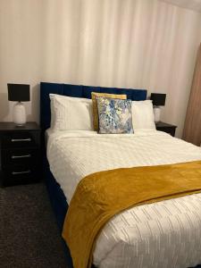 1 Schlafzimmer mit einem Bett mit blauem Kopfteil und 2 Lampen in der Unterkunft Sycamore Retreat in Kettering