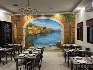 a dining room with tables and a painting of a river at Ammania Hotel in Amman